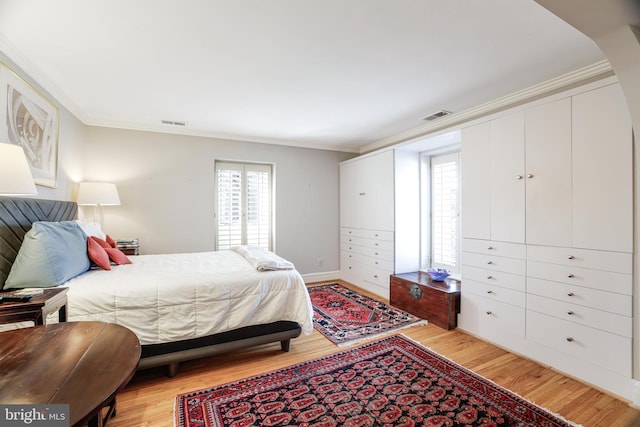 bedroom with light wood-type flooring, visible vents, and crown molding