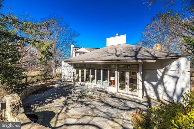 back of house featuring a shingled roof, fence, french doors, a chimney, and a patio