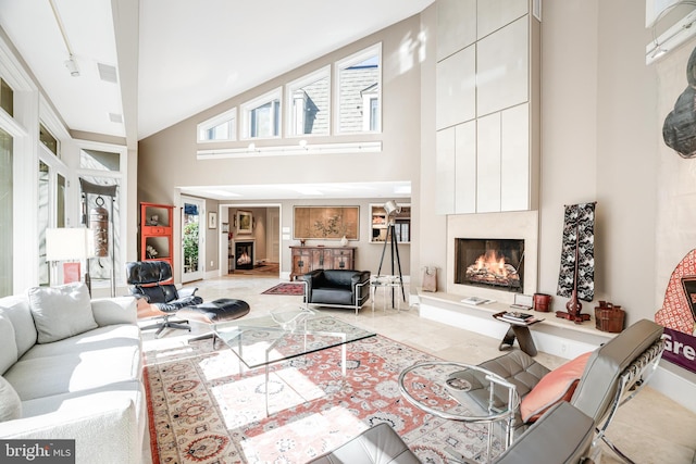 tiled living room with baseboards, visible vents, a towering ceiling, and a large fireplace