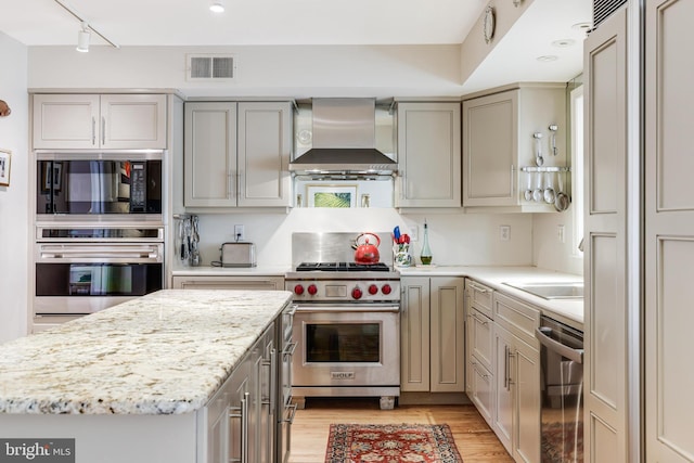 kitchen with gray cabinets, wall chimney exhaust hood, visible vents, and stainless steel appliances