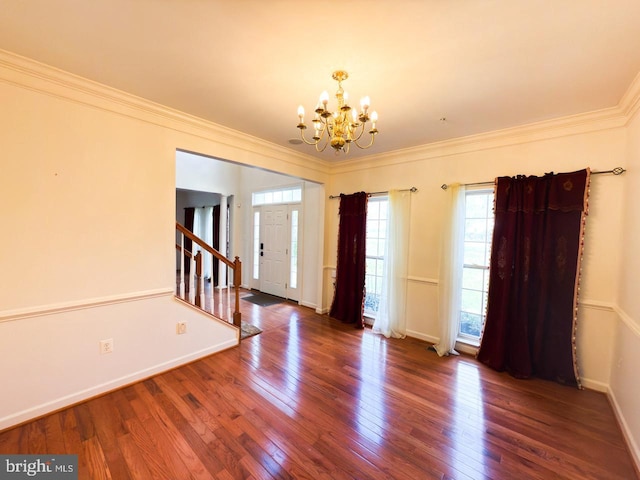 foyer entrance with wood-type flooring, crown molding, baseboards, and an inviting chandelier