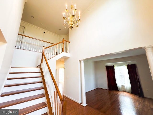 stairs featuring an inviting chandelier, a healthy amount of sunlight, wood finished floors, and ornate columns