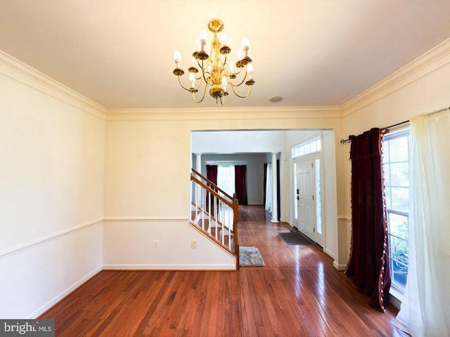 foyer featuring baseboards, a notable chandelier, wood finished floors, stairway, and crown molding