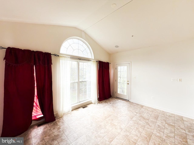 tiled empty room with vaulted ceiling, a healthy amount of sunlight, and visible vents