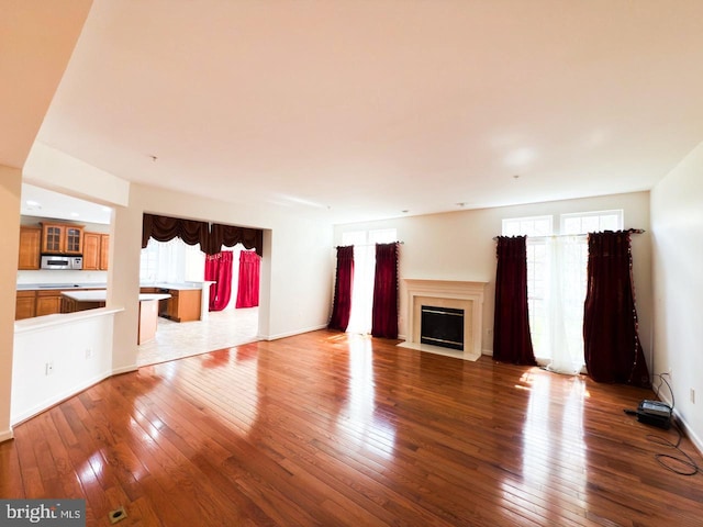 unfurnished living room featuring hardwood / wood-style floors, a fireplace with flush hearth, and a healthy amount of sunlight