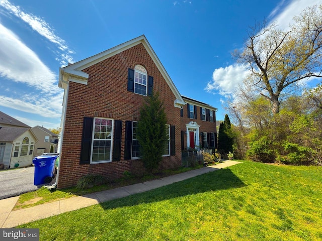 view of side of property with brick siding and a yard