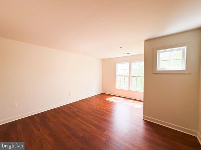 empty room featuring baseboards and dark wood-style flooring