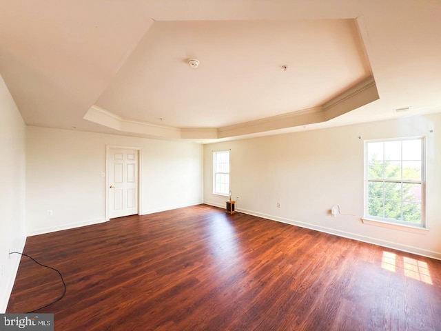 empty room featuring ornamental molding, baseboards, dark wood-style flooring, and a tray ceiling