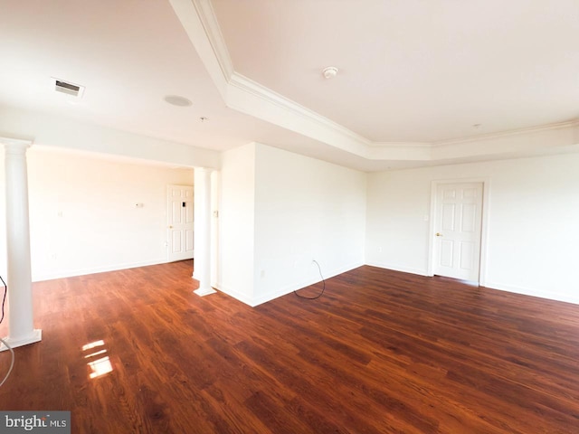 spare room with a tray ceiling, wood finished floors, visible vents, crown molding, and decorative columns