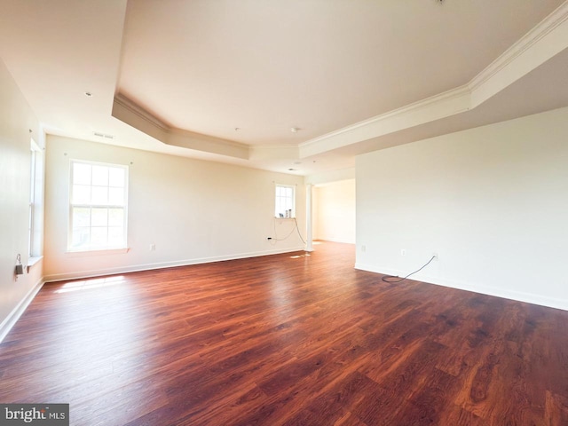 spare room featuring a tray ceiling, baseboards, dark wood-style floors, and ornamental molding