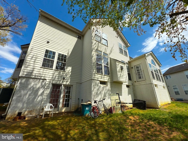 back of property with brick siding and a yard