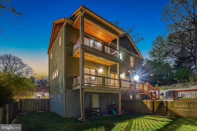 rear view of house with a lawn, stairway, a balcony, and a fenced backyard