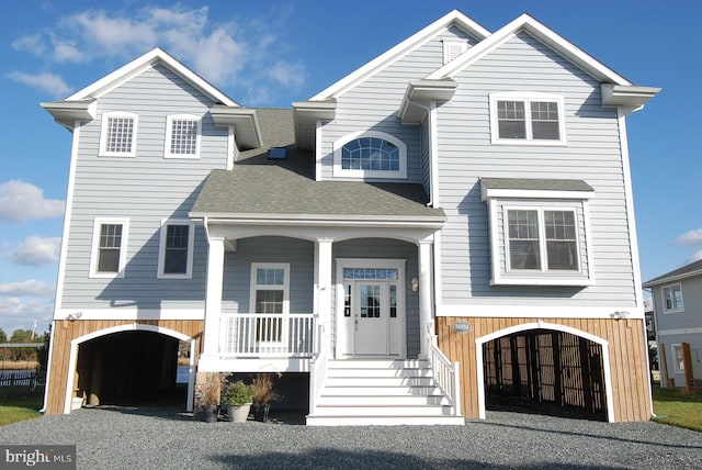 view of front of home with covered porch, driveway, and roof with shingles