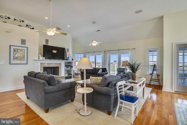 living area with baseboards, visible vents, light wood-type flooring, and a tile fireplace