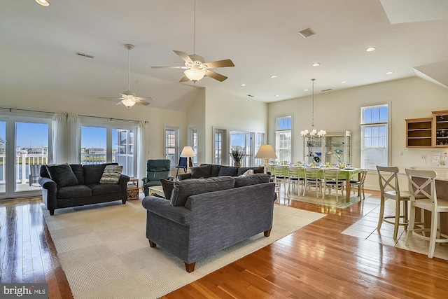 living area with an inviting chandelier, plenty of natural light, light wood-style floors, and high vaulted ceiling