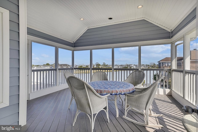 sunroom with lofted ceiling and a water view