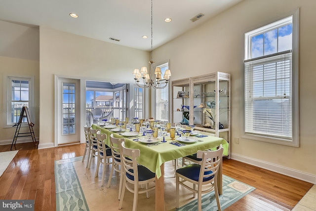 dining room featuring a chandelier, visible vents, baseboards, and hardwood / wood-style flooring