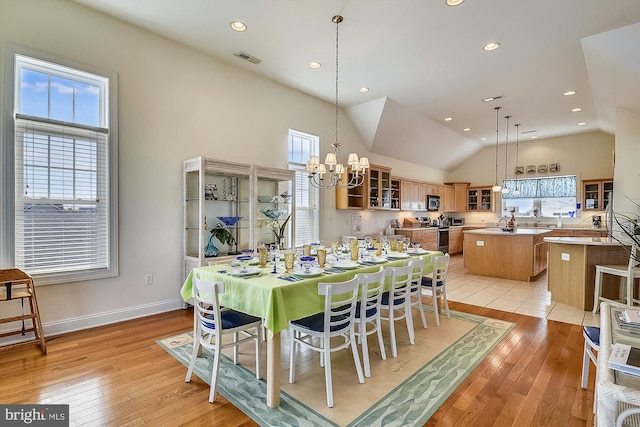 dining room with visible vents, light wood-style floors, baseboards, a chandelier, and vaulted ceiling