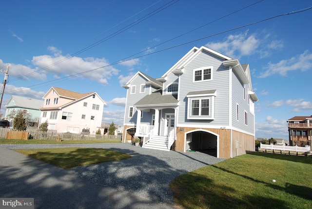 view of front of house with gravel driveway, a front lawn, and fence