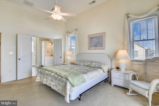 bedroom featuring visible vents, light colored carpet, baseboards, and connected bathroom