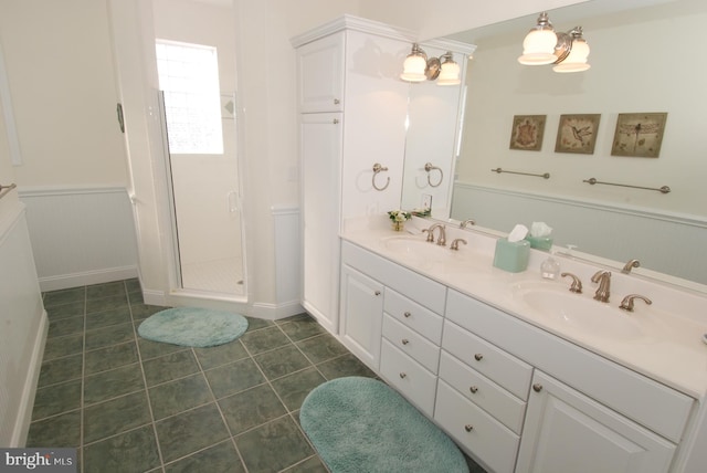 bathroom with a sink, a stall shower, wainscoting, and tile patterned flooring