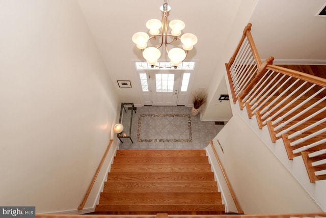 stairs with a chandelier, baseboards, and wood finished floors