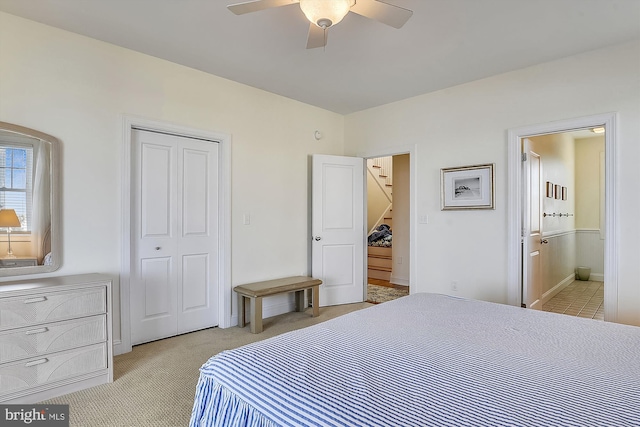 bedroom featuring a ceiling fan, a closet, ensuite bathroom, and light carpet