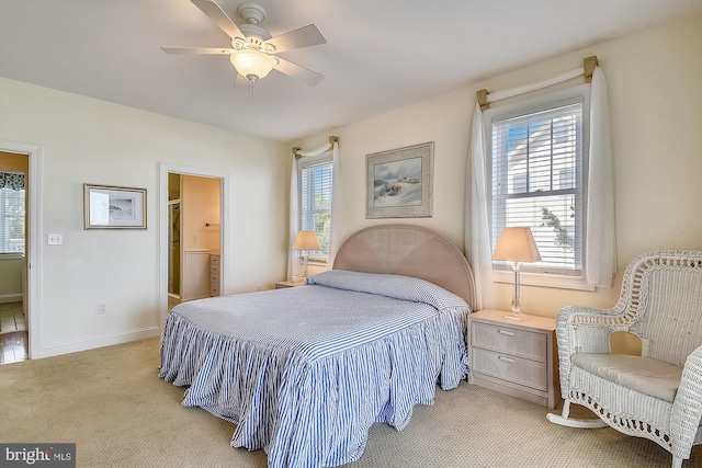 bedroom with light carpet, connected bathroom, a ceiling fan, and baseboards