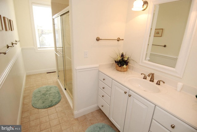 bathroom with a wainscoted wall, a shower stall, and vanity