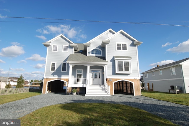 view of front of house featuring a front lawn, fence, roof with shingles, covered porch, and driveway