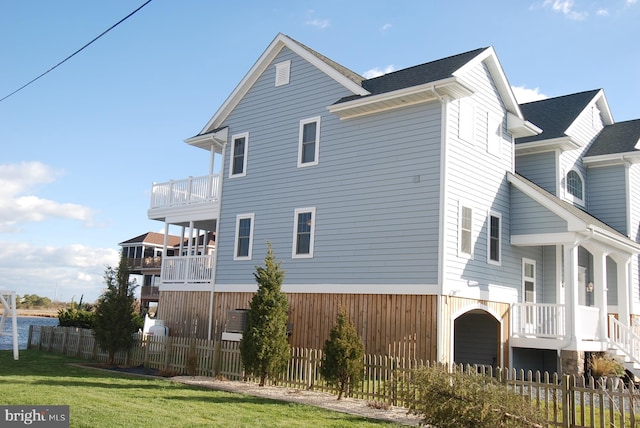 view of home's exterior featuring a balcony, a lawn, and a fenced front yard