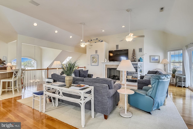 living room featuring visible vents, high vaulted ceiling, light wood-style flooring, recessed lighting, and a fireplace