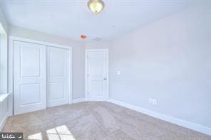 unfurnished bedroom featuring carpet, baseboards, and a closet