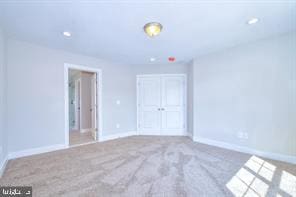 unfurnished bedroom with recessed lighting, a closet, baseboards, and carpet flooring