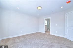 unfurnished bedroom featuring baseboards, ensuite bathroom, and carpet