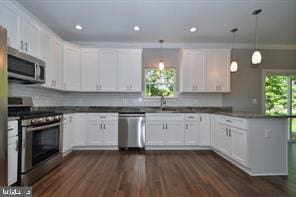 kitchen with dark countertops, white cabinets, appliances with stainless steel finishes, and a peninsula