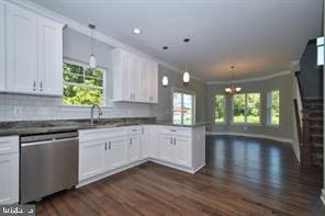 kitchen with dark countertops, stainless steel dishwasher, a peninsula, and white cabinetry