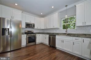 kitchen featuring dark countertops, dark wood-type flooring, decorative light fixtures, appliances with stainless steel finishes, and white cabinets