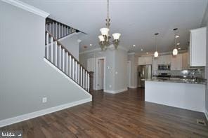 kitchen with dark wood-style floors, baseboards, appliances with stainless steel finishes, pendant lighting, and crown molding