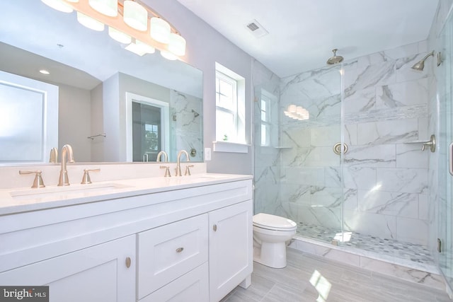 bathroom with a marble finish shower, visible vents, toilet, and a sink