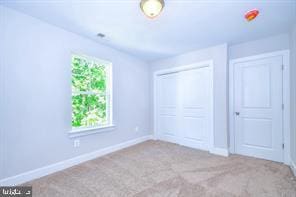 unfurnished bedroom featuring carpet, baseboards, and a closet