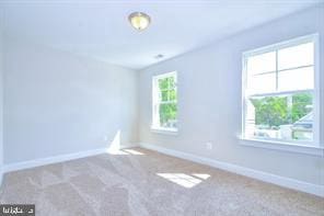 carpeted spare room featuring baseboards