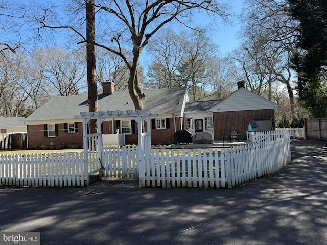 view of front facade featuring brick siding, a chimney, a pergola, and fence