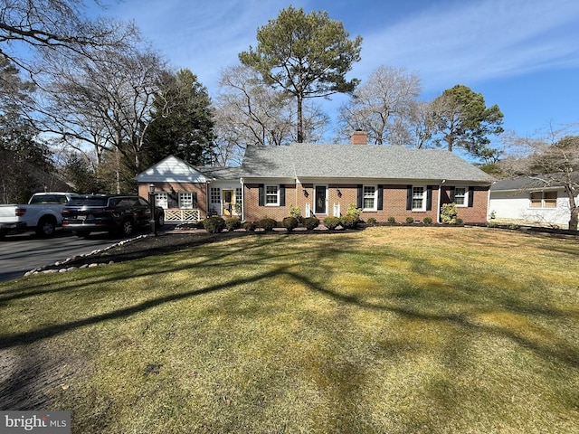 view of front of house with a front yard, brick siding, and a chimney