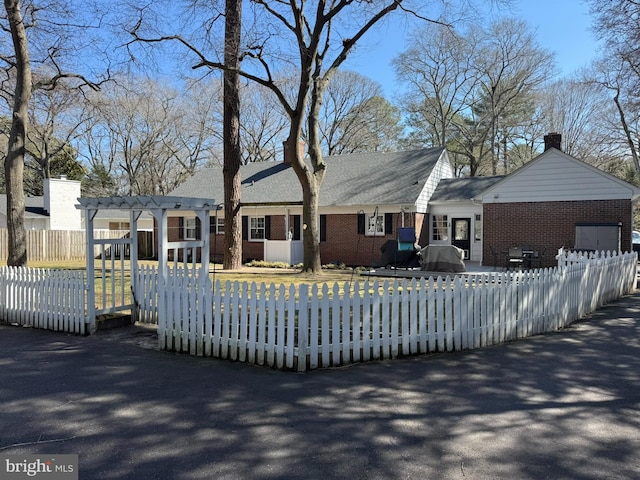 view of front of house with brick siding, a pergola, and a fenced front yard