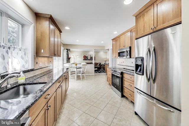 kitchen featuring backsplash, light tile patterned flooring, a sink, appliances with stainless steel finishes, and a wealth of natural light