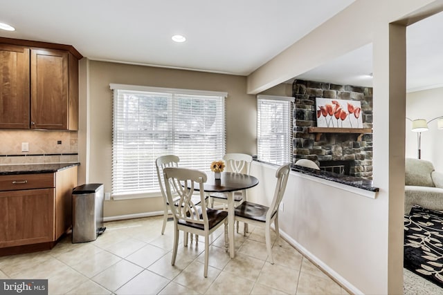 dining room featuring a wealth of natural light, a stone fireplace, and light tile patterned floors