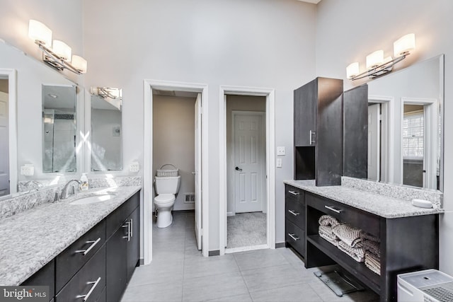 bathroom with visible vents, baseboards, toilet, a high ceiling, and vanity