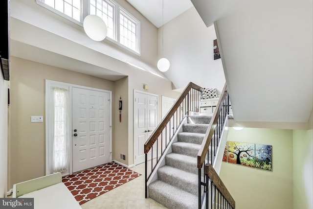 foyer featuring baseboards, a high ceiling, stairs, and tile patterned flooring