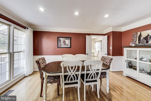 dining space with light wood finished floors, visible vents, wainscoting, and crown molding